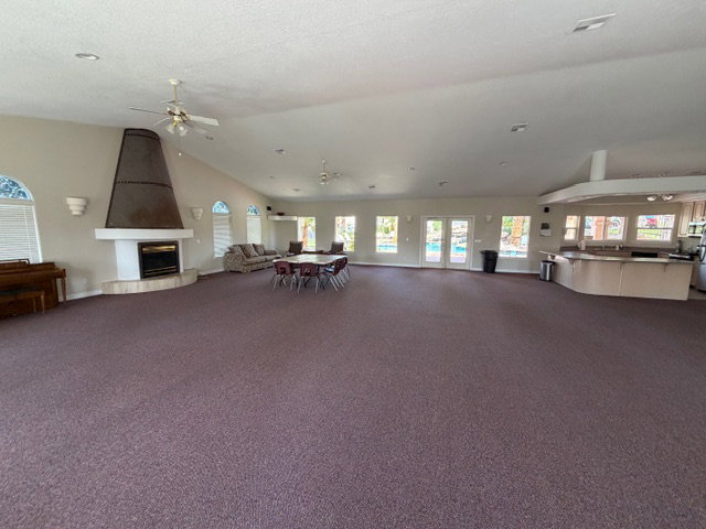 Misc room with lofted ceiling, a ceiling fan, and a large fireplace