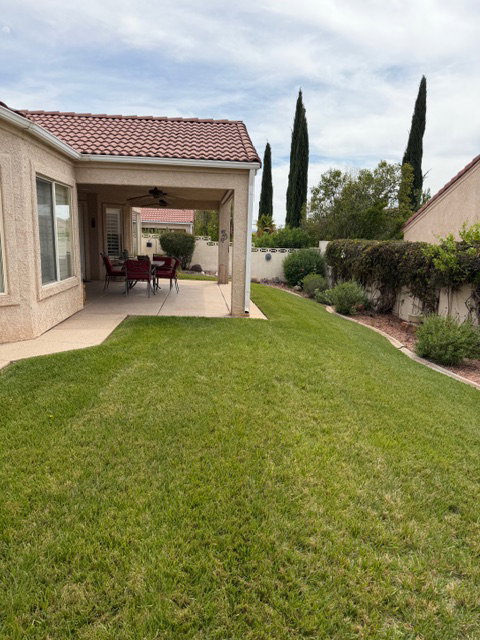 Fenced backyard featuring ceiling fan and a patio