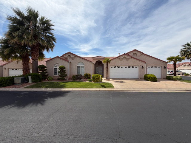 Mediterranean / spanish-style house with an attached garage, stucco siding, concrete driveway, and a front yard