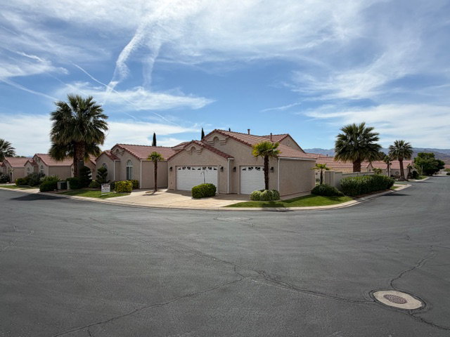 View of front facade featuring a garage, a residential view, stucco siding, and concrete driveway