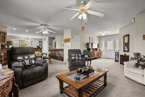 Carpeted living room featuring ceiling fan and a textured ceiling