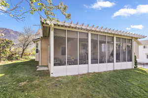 Rear view of house with a yard, a sunroom, and a mountain view