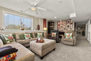 Living area with carpet, a ceiling fan, a textured ceiling, and recessed lighting