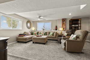 Carpeted living room with a textured ceiling, a ceiling fan, and recessed lighting
