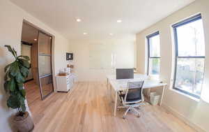 Office area featuring light wood-style floors and recessed lighting