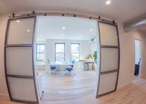 Office with light wood-style floors and recessed lighting