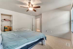 Bedroom featuring light carpet, a ceiling fan, and a walk in closet