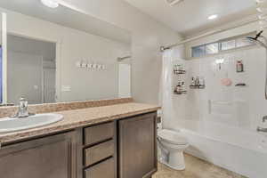 Full bath with vanity, shower / bath combo with shower curtain, and light tile patterned floors
