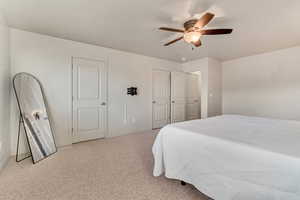 Bedroom with light carpet and a ceiling fan