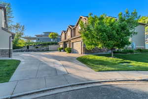 View of home's exterior featuring an attached garage, driveway, a residential view, a yard, and stucco siding