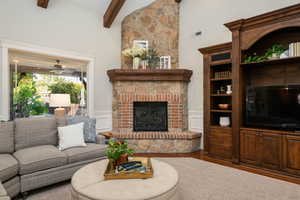 Living area featuring lofted ceiling, wood finished floors, a large fireplace, a wainscoted wall, and a decorative wall