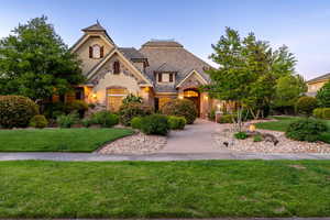 French country home featuring stone siding, a front lawn, and stucco siding