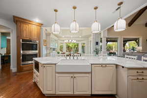 Kitchen featuring stainless steel appliances, light stone countertops, arched walkways, open floor plan, and dark wood finished floors