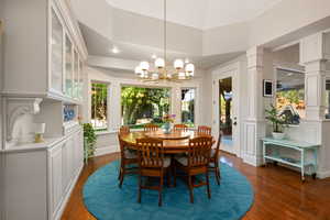 Dining space with hanging lights, dark wood finished floors, and decorative columns