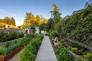 View of property's community with a fenced backyard, a storage unit, and a garden
