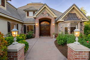 View of exterior entry with brick siding, a standing seam roof, stone siding, and stucco siding