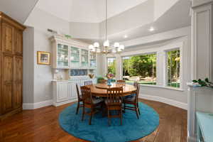 Dining space featuring dark wood-style floors, suspended lighting, plenty of natural light, and vaulted ceiling