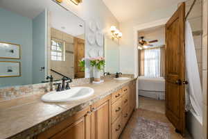 Ensuite bathroom with a tile shower, double vanity, ceiling fan, and light tile patterned floors