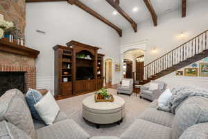 Living room featuring a decorative wall, wainscoting, arched walkways, a brick fireplace, and recessed lighting
