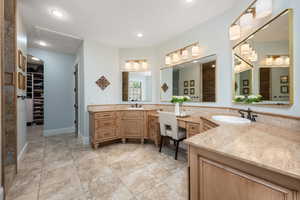 Bathroom with two vanities, a walk in closet, and recessed lighting