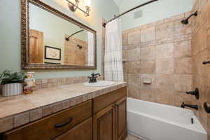 Bathroom featuring shower / bathtub combination with curtain and vanity