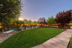 Yard at dusk with a fenced backyard and a patio area