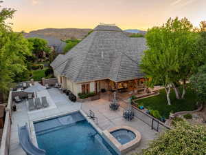 Rear view of property featuring outdoor dining area, a shingled roof, a patio area, and a mountain view