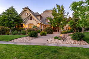 View of front of property featuring stone siding, a front yard, and stucco siding