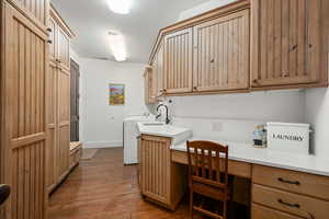 Laundry area with dark wood finished floors, a desk, cabinet space, and washer and clothes dryer