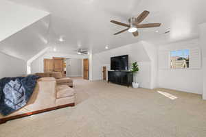Living room with ceiling fan, light colored carpet, and lofted ceiling