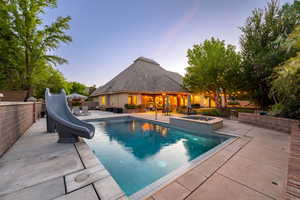 View of swimming pool featuring a fenced backyard, an in-ground hot tub, a water slide, and patio surround