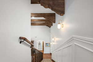 Stairs featuring arched walkways, a decorative wall, a wainscoted wall, and wood finished floors