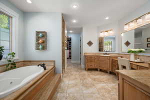 Bathroom with vanity, recessed lighting, a tub with jets, light tile patterned floors, and a walk in closet