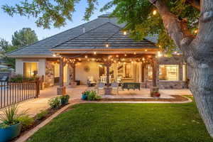 Rear view of house with stone siding, a patio, a yard, and stucco siding
