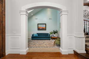 Interior space with wainscoting, a decorative wall, wood finished floors, decorative columns, and recessed lighting