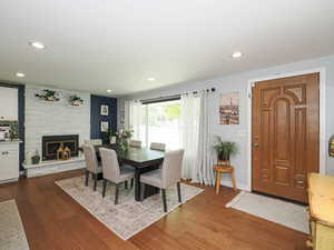 Dining room with dark wood-style floors, a fireplace, and recessed lighting