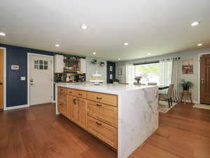 Kitchen featuring a center island, open shelves, recessed lighting, light stone countertops, and dark wood-type flooring