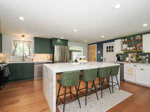 Kitchen featuring backsplash, stainless steel appliances, light stone counters, a kitchen island, and recessed lighting