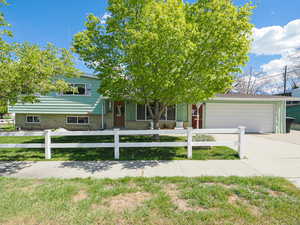 View of front of house featuring a fenced front yard, concrete driveway, a garage, and covered porch