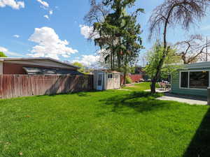 Fenced backyard featuring a storage unit and a patio area