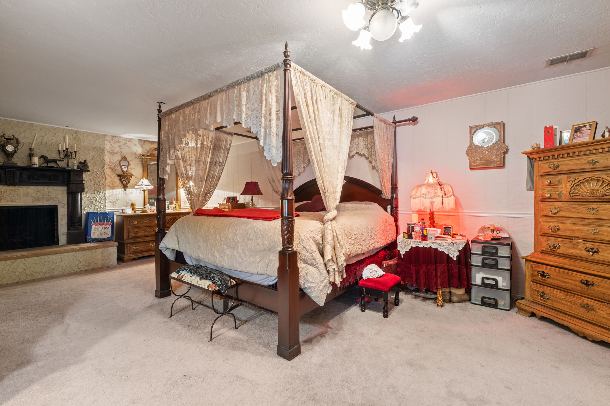Bedroom featuring light carpet, a fireplace with raised hearth, and a textured ceiling