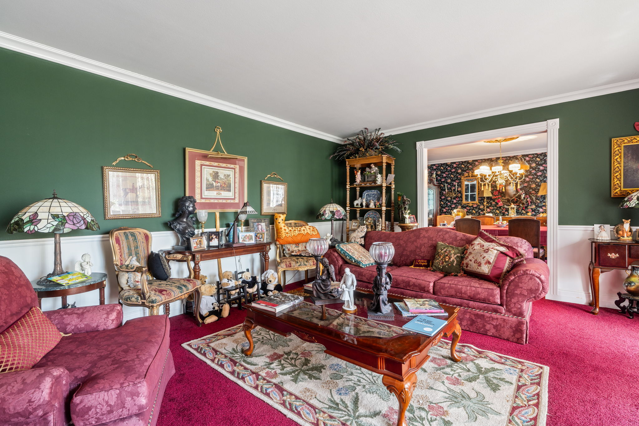 Living area featuring a chandelier, carpet floors, crown molding, and wainscoting