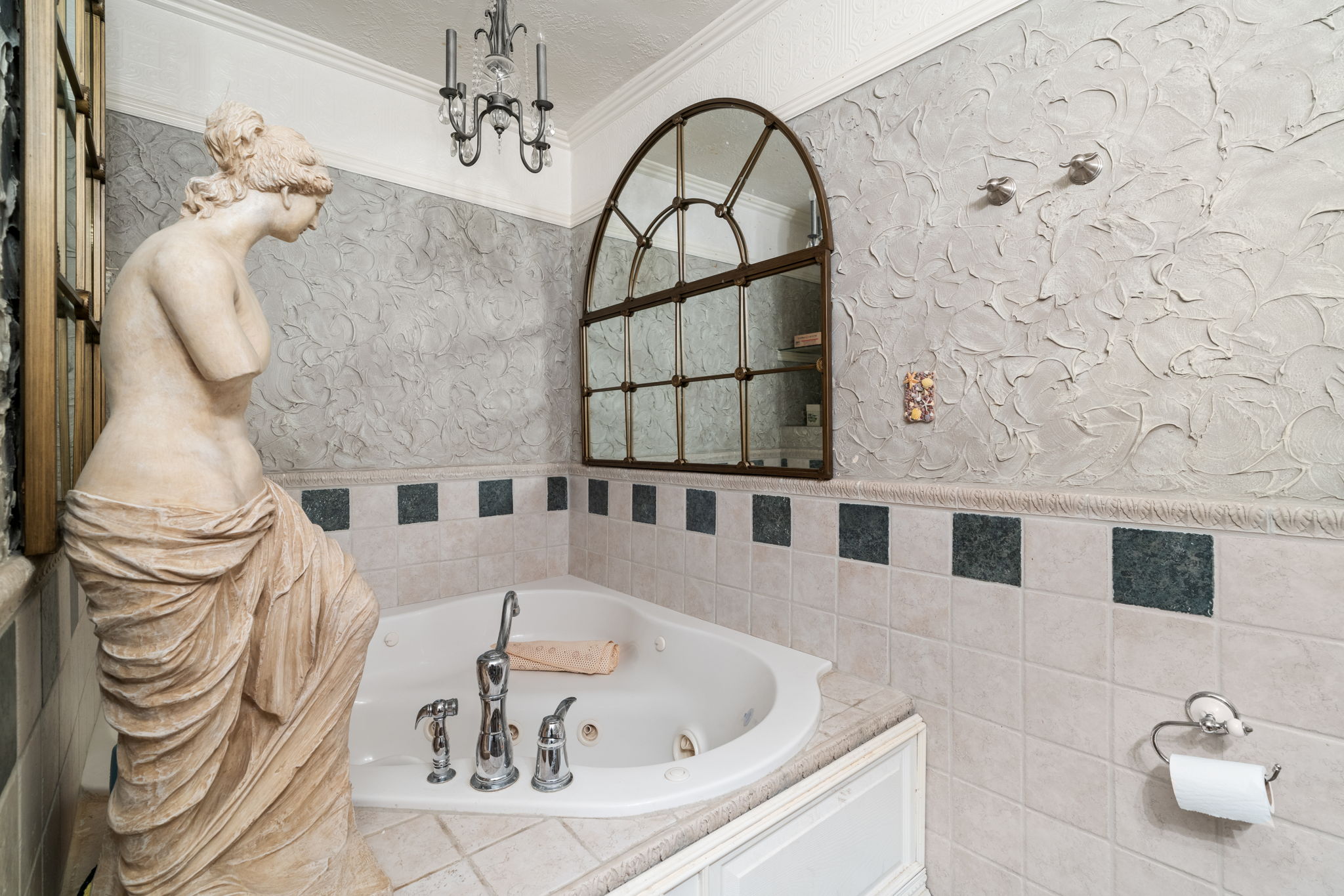 Full bathroom featuring a tub with jets, crown molding, wainscoting, a textured wall, and tile walls