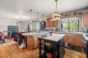 Kitchen featuring tile counters, wood finish cabinetry, light wood-type flooring, and crown molding