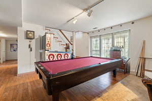 Game room featuring light wood-type flooring, billiards table, a textured ceiling, and track lighting
