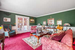 Living area featuring french doors, a wainscoted wall, carpet flooring, and crown molding