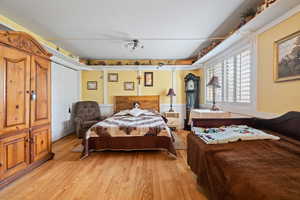 Bedroom featuring wainscoting, a closet, light wood-type flooring, and a decorative wall