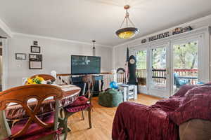 Living room with light wood-type flooring, ornamental molding, and french doors