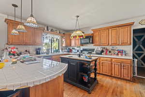 Kitchen with tile counters, wood finish cabinets, and light wood-style flooring