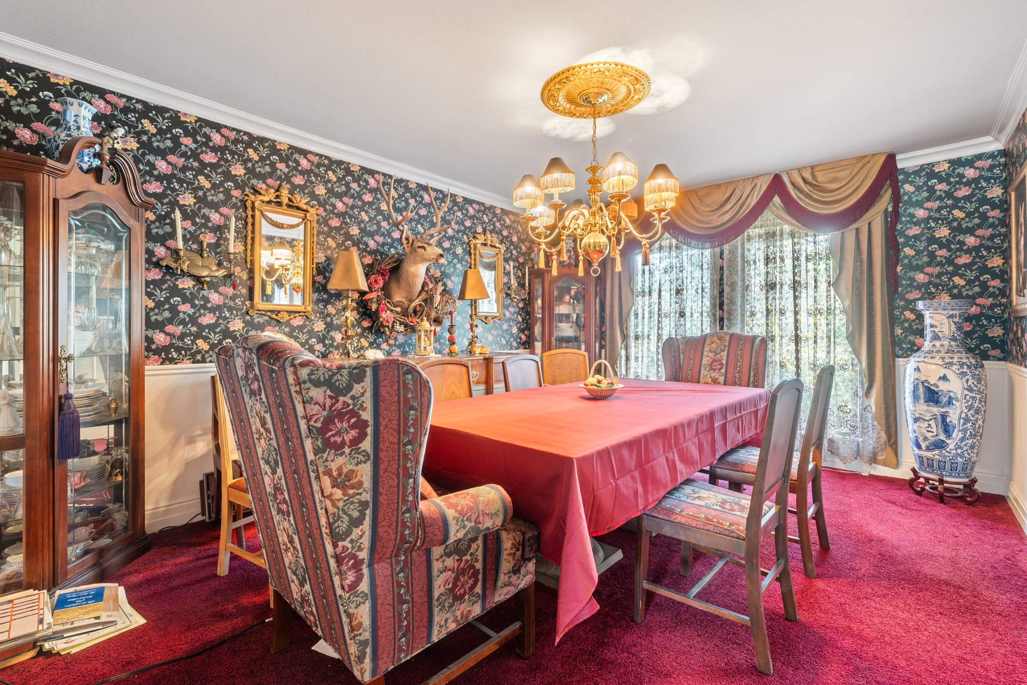 Dining room with wallpapered walls, ornamental molding, hanging lights, and carpet flooring